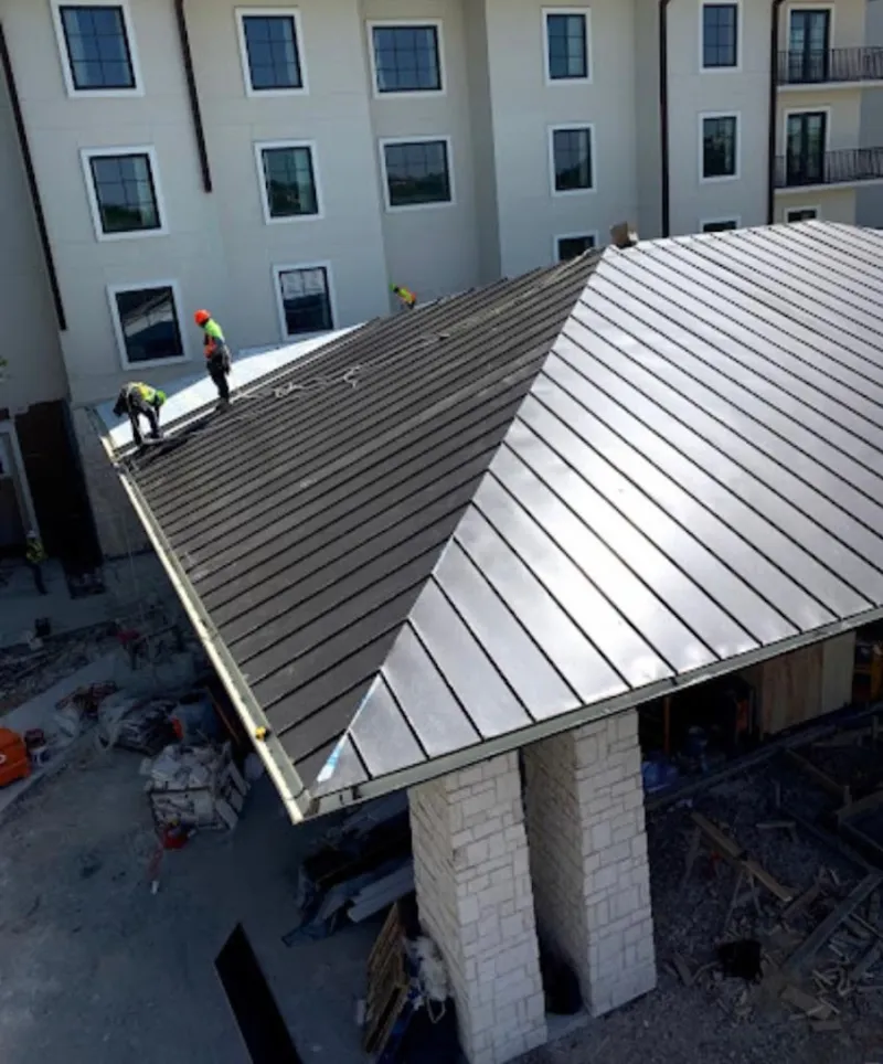 Crew installing standing seam metal roof panels on a commercial project in Barnesville